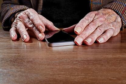 Las manos de una persona mayor sujetan un móvil.
