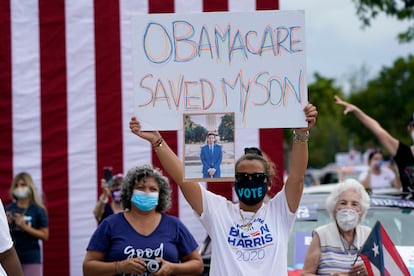 La venezolana Adelys Ferro sostiene una pancarta en la que se lee "Obamacare salvó a mi hijo" en un evento de campaña de Joe Biden en Miami.