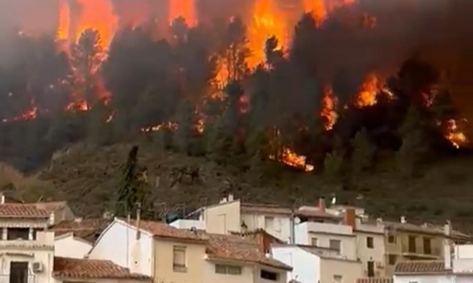 Los medios de extinción trabajan en la defensa del núcleo de Montán (Castellón), rodeado por el fuego, este lunes.