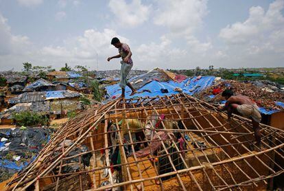 Dos hombres de la etnia rohingya reparan el tejado de su infravivienda en el campamento de refugiados de Kutupalang en el Cox's Bazar, Bangladesh.