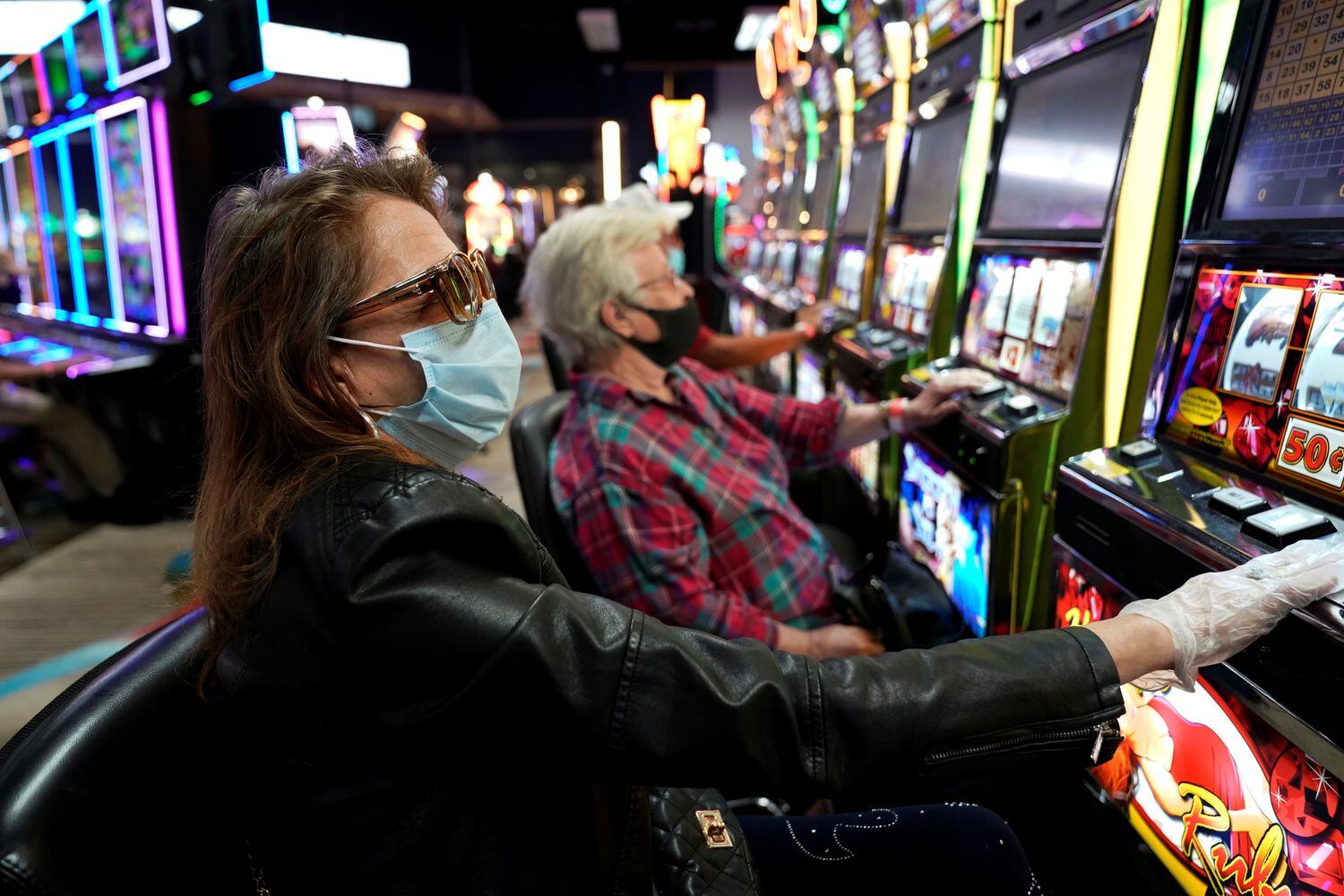 Una mujer con mascarilla y guantes juega en el casino Lucky Star, que ha vuelto abrir al público, en El Reno, Oklahoma (EE UU).