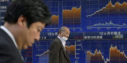 Dos hombres junto a una pantalla de la Bolsa en Tokio (Japón).
