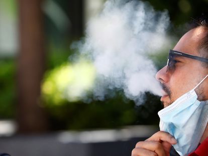 Un hombre expulsa el humo del tabaco mientras fuma sentado en una calle en Córdoba.