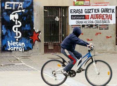 Un niño pasa en bicicleta en marzo ante una pintada de ETA en Pamplona.