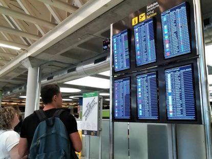 Dos viajeros consultan la información de vuelos en las pantallas del aeropuerto.