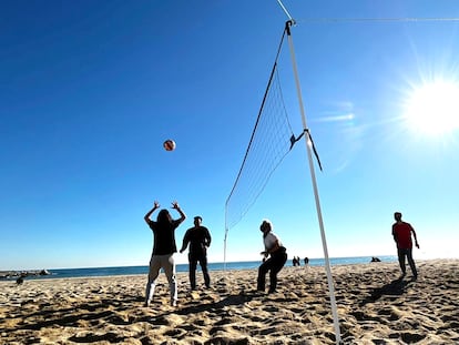 Adolescentes juegan a voleibol en una playa.