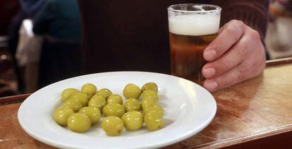 Un cliente ante una caña de cerveza y un plato de aceitunas en un bar de Madrid.