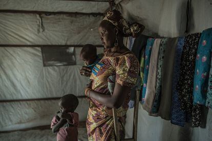 Una mujer posa en el interior de su cabaña con sus dos hijos, todos huidos de los ataques de Boko Haram.