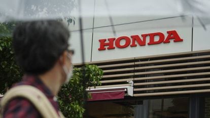 Un hombre con mascarilla mira el logo de Honda.