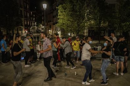 Un grupo de jóvenes baila pasadas las doce de la noche en la plaza de Isabel II, junto a Opera, en Madrid.