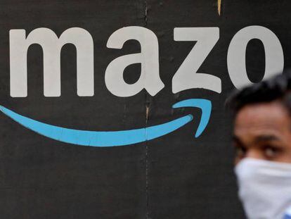 Una persona pasa junto a un logo de Amazon.