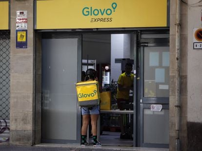 Un rider de Glovo frente a un supermercado express de la compañía de reparto a domicilio en Barcelona.