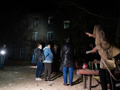 Varias personas observaban un edificio de apartamentos de tres plantas dañado tras un ataque ruso con drones el 4 de abril de 2024 en Járkov.