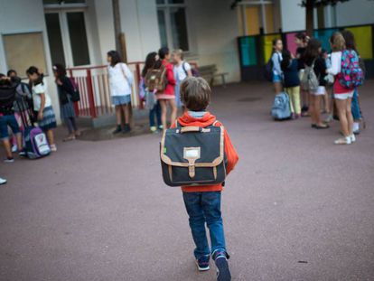 Un ni&ntilde;o con mochila en el patio de un colegio. 