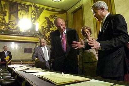Los Reyes reciben las explicaciones del bibliotecario jefe de la ONU en Ginebra, Pierre Le Loarer (derecha).