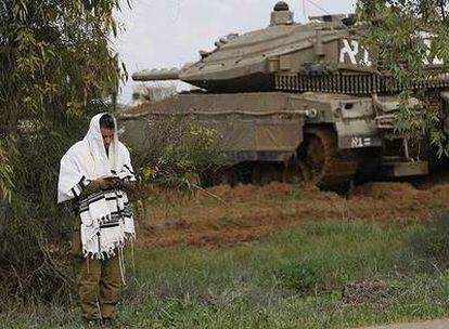 Un soldado israelí reza junto a un carro blindado en el despliegue del Ejército cerca de la frontera con Gaza.