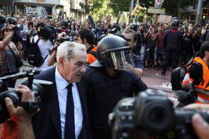 Ernest Maragall, del PSC, escoltado por los mossos durante la concentración de indignados las puertas del Parlament de Cataluña.