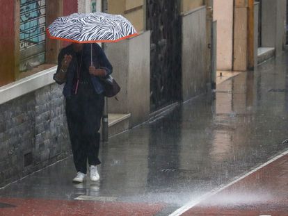 Una mujer se protege de la lluvia este viernes en Valencia a primeras horas.