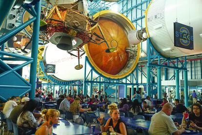 Hora del almuerzo para los turistas, bajo el cohete Saturn V.