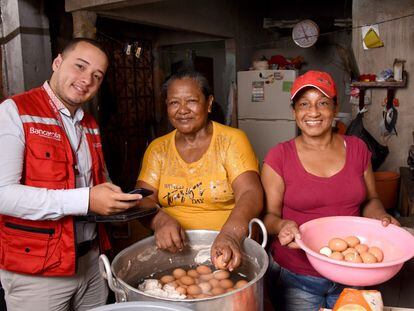 Un asesor de Bancamía, de la Fundación Microfinanzas BBVA en Colombia, atiende a unas clientas en su negocio.