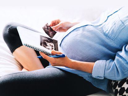 Una mujer embarazada sostiene una ecografía.