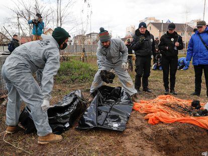 Forenses ucranios colocan este martes en bolsas para cadáveres restos quemados de civiles exhumados en Bucha.