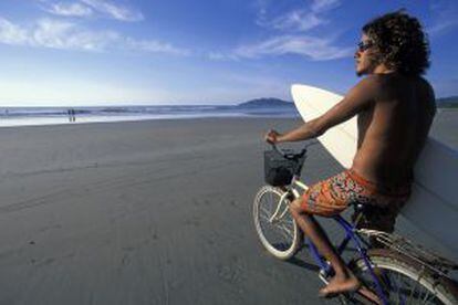 Un surfista montado en su bicicleta en una de las playas de la reserva natural de Tamarindo, en Costa Rica.