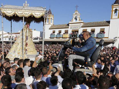 Un peregrino en una silla de ruedas motorizada es alzado por la multitud para poder aproximarse a la virgen del Rocío, en Almonte, Huelva (España).