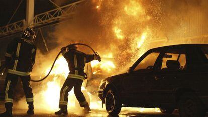 Foto de noviembre de 2005 que muestra a bomberos extinguiendo un incendio en un coche incendiado al sur de Par&iacute;s. 
