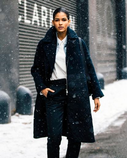 Este es uno de los looks favoritos de las modelos como Cris Urena que eligen camiseta blanca y abrigo negro largo y de silueta cocoon.