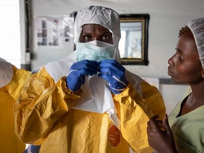 Un médico se viste con el EPI para entrar en la zona de alto riesgo del Centro de Tránsito del Ébola en Bunia (República Democrática del Congo) en junio de 2019.