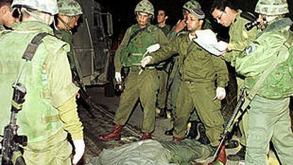Soldados israelíes rodean el cadáver de una de las víctimas del ataque palestino en Cisjordania.