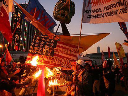 Manifestantes contra la Organización Mundial de Comercio queman una bandera estadounidense, ayer en Hong Kong.