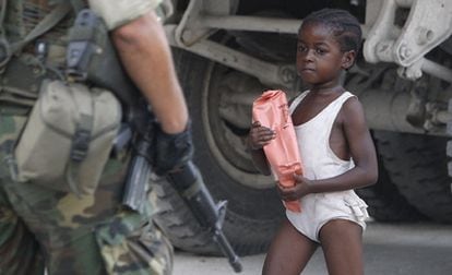 Una niña camina en mitad de un cordón de seguridad de los soldados estadounidenses en una calle de Puerto Príncipe.