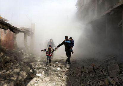 Ciudadanos sirios huyen de los ataques aéreos del régimen en la ciudad de Jisreen, controlada por los rebeldes, a las afueras de Damasco (Siria).