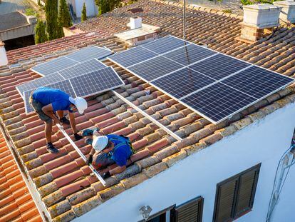Dos operarios instalan paneles solares en una vivienda.