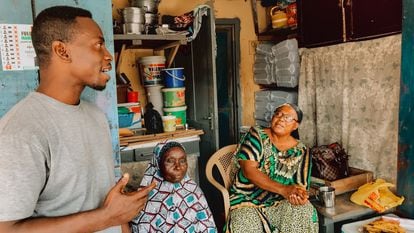 El pastor protestante Justice Obeng, a la izquierda, con dos mujeres musulmanas sentadas a la puerta de su casa en Nima (Accra).