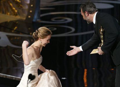 La actriz Jennifer Lawrence es ayudada a levantarse por el actor francés Jean Dujardin, tras su caída cuando subía las escaleras del escenario. Recoge el premio al Oscar a la mejor actriz por 'El lado bueno de las cosas'.