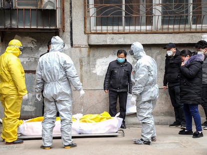 Un grupo de trabajadores sanitarios transporta el cuerpo de un fallecido con covid-19, en febrero en Wuhan (China).