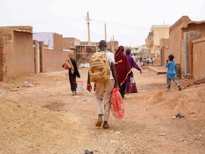 Personas cargan sus pertenencias mientras caminan por una calle de Omdurman, la ciudad gemela de la capital en Sudán, devastada por la guerra, el lunes pasado.