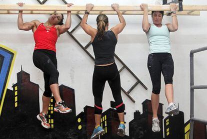 Tres de las mujeres aspirantes a bomberas se entrenan en un gimnasio para las difíciles pruebas de ingreso.