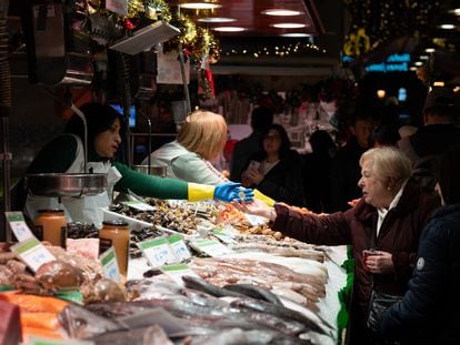 Una comerciante cobra a una señora, en el Mercado de la Boquería, en Barcelona.