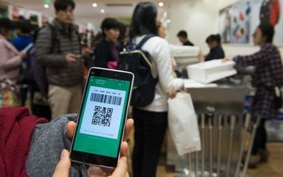 Una compradora muestra el c&oacute;digo temporal generado por WeChat Pay en una tienda de la cadena japonesa Uniqlo en Shangh&aacute;i.
