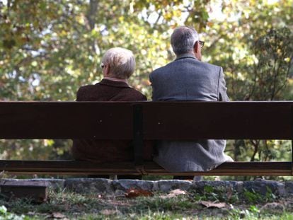 Dos ancianos, sentados en un banco de un parque público de Madrid.
