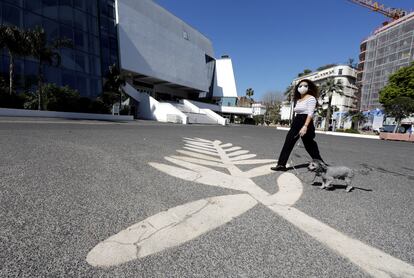 Una mujer lleva una máscara ante un símbolo de la Palma de Oro pintado en el paseo de la Croisette, donde se celebra el Festival de Cannes, en Francia, el pasado 18 de marzo .