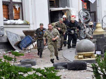 Milicianos prorrusos y bomberos se alejan de la sede regional de Donetsk.