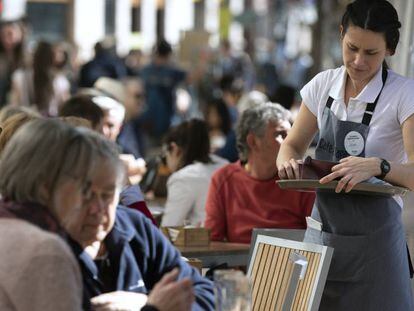 Una camarera atiende a unos clientes en una terraza en Valencia.