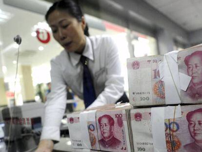 Empleada del Banco Comercial e Industrial de China, dando billetes de renminbi a un cliente.