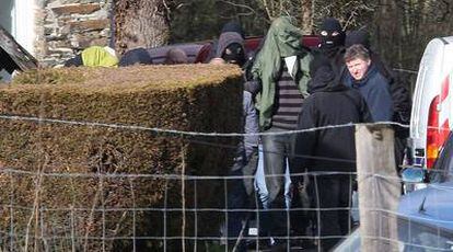 Agentes policiales conducen a uno de los detenidos ayer en Cahan (en el centro, con camiseta a rayas) durante el registro de la casa rural donde se alojaban en Normandía.