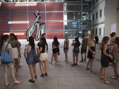 Un grupo de jóvenes turistas esperan para comprar su entrada del Museo Reina Sofía junto a la escultura 'Brushstroke' de Roy Lichtenstein.